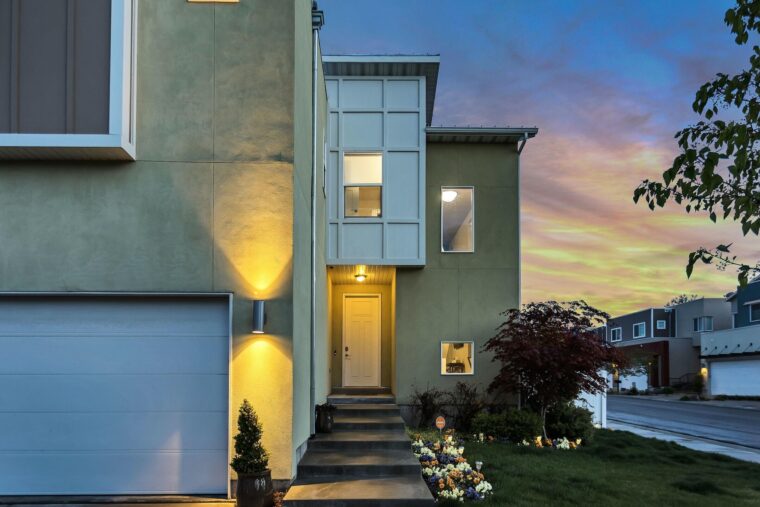 Large stairs leading to the front door of a green home are painted black.